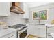 Updated kitchen with stainless steel appliances, designer range hood, white countertops, and wood-trimmed windows at 9810 Venneford Ranch Rd, Highlands Ranch, CO 80126