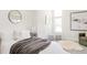 Bright bedroom with a comfortable bed, round mirror, and seating area by the window at 1390 S Jasmine Way, Denver, CO 80224