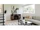 Bright living room features a modern sofa, black coffee table, media cabinet, and a large window at 1390 S Jasmine Way, Denver, CO 80224