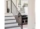 Staircase with modern railings, leading to a well-decorated space with artwork and console table at 1390 S Jasmine Way, Denver, CO 80224