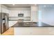 Bright kitchen with white cabinets, stainless steel appliances, island with a sink, and hardwood floors at 21242 E 63Rd Dr, Aurora, CO 80019