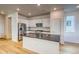 Bright kitchen with white cabinets, stainless steel appliances, island with sink, and hardwood floors at 21242 E 63Rd Dr, Aurora, CO 80019