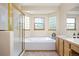 Bright bathroom featuring a soaking tub with tile surround and a glass-enclosed shower at 6506 S Robb Way, Littleton, CO 80127