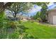 Well-manicured front yard with green lawn, mature trees, and flowering plants at 6506 S Robb Way, Littleton, CO 80127