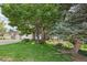 Beautiful front yard featuring mature trees, lush lawn and colorful landscaping in front of this brick and siding home at 6506 S Robb Way, Littleton, CO 80127