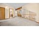 Open loft area with wood railings, neutral carpet, and stairs to another level at 6506 S Robb Way, Littleton, CO 80127
