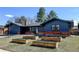 Inviting single-story home featuring a beautiful blue exterior with brick accents and wooden raised garden beds at 7476 Park Lane Rd, Longmont, CO 80503