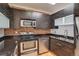 Modern kitchen with stainless steel appliances, dark wood cabinetry, black countertops, and brick backsplash at 2306 Glenarm Pl # 206, Denver, CO 80205