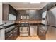 Sleek kitchen features dark cabinetry, stainless steel appliances, brick backsplash, and modern lighting at 2306 Glenarm Pl # 206, Denver, CO 80205
