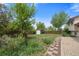 A spacious backyard oasis featuring lush grass, mature trees, lovely flowering plants, and a storage shed at 2453 S Memphis Way, Aurora, CO 80013