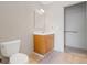 Well-lit bathroom featuring wood vanity, sink, mirror, toilet, and light-colored floor at 2453 S Memphis Way, Aurora, CO 80013