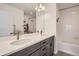 Bright bathroom featuring double sinks, modern fixtures, and a combined shower-tub with white tile surround at 14734 Domino Dr, Parker, CO 80134