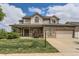Charming two-story home featuring a covered front porch, brick accents, an attached garage, and a well-manicured lawn at 5483 Gunnison Dr, Frederick, CO 80504