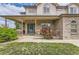 Inviting covered front porch with brick details and a well-maintained lawn with green door at 5483 Gunnison Dr, Frederick, CO 80504