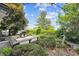 Private backyard with mature trees, lush greenery, and wooden deck with seating at 10150 Melody Dr, Northglenn, CO 80260