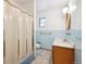 Classic bathroom featuring blue tile, wood vanity, and shower with curtain at 10150 Melody Dr, Northglenn, CO 80260