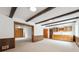 Open-concept living room with exposed beams, wood paneling and wet bar with cabinets at 10150 Melody Dr, Northglenn, CO 80260