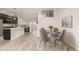 Open dining area with a glass table, gray chairs, and light wood floors that connects to the kitchen at 619 Brennan Cir, Erie, CO 80516