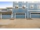 Exterior view of garages and townhomes with matching blue siding, doors, and gray stone trim at 619 Brennan Cir, Erie, CO 80516