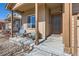 Cozy front porch features comfortable seating, a wood support structure and a brown front door at 1820 Taos St, Brighton, CO 80603