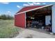 Large red outbuilding with open sliding doors, equipment inside, and adjacent open space for parking at 5537 Lake Gulch Rd, Castle Rock, CO 80104