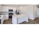 Modern kitchen with white cabinets, stainless steel appliances, large island, and wood-look flooring at 15285 Milwaukee St, Thornton, CO 80602