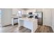 Bright kitchen featuring stainless appliances, white cabinets, a kitchen island, and wood-look flooring at 15285 Milwaukee St, Thornton, CO 80602