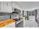 Modern kitchen with stainless steel appliances, butcher block countertops, and view to dining area at 1287 S Wheeling Way, Aurora, CO 80012