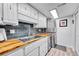 This kitchen features white cabinets, butcher block countertops, stainless steel appliances, and a stacked washer/dryer at 1287 S Wheeling Way, Aurora, CO 80012