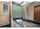 Bathroom with a granite countertop, a glass block window, a large mirror, and tiled floors at 8530 W Jefferson Ave, Denver, CO 80235