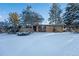 Charming brick home with a snow-covered front yard and mature trees at 8530 W Jefferson Ave, Denver, CO 80235