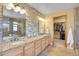 Elegant main bathroom featuring double sinks, granite countertops, stone accent wall, and a walk-in closet at 3644 Sunchase Dr, Castle Rock, CO 80109