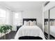 Bright bedroom featuring a dark wood bedframe, white bedding, sheer curtains, and a mirrored closet door at 11745 Newton St, Westminster, CO 80031