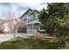 Charming two-story home featuring green siding, stone accents, a well-manicured lawn, and mature landscaping at 19634 E Clear Creek Trl, Parker, CO 80134