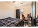 This bedroom features a bed, a computer desk with a bright orange chair, gray carpet, and a window at 15685 E 50Th Ave, Denver, CO 80239