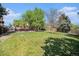 Backyard with a lush green lawn, patio, mature trees, and a wooden fence at 1572 W Long Ave, Littleton, CO 80120