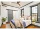 Comfortable bedroom with a ceiling fan, sliding barn door, hardwood floors, and large windows with dark trim at 2939 Osceola St, Denver, CO 80212