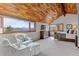 Spacious primary bedroom featuring vaulted wood ceilings, cozy seating area, and scenic mountain views from the large windows at 2063 Montane E Dr, Golden, CO 80401