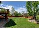 Landscaped backyard with large lawn, mature trees, and a wood deck at 879 Quintana Ln, Erie, CO 80516