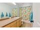 Bathroom with tile floors, wood cabinets, and a colorful owl-themed shower curtain at 879 Quintana Ln, Erie, CO 80516