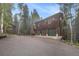 Three-story wooden home with a three-car garage surrounded by tall trees at 10419 Christopher Dr, Conifer, CO 80433