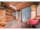 Charming living room with wood paneled walls and ceiling, complemented by a comfortable red chair at 10419 Christopher Dr, Conifer, CO 80433