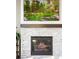 Close-up of a modern fireplace with a stone surround, a wooden mantel, and a mounted TV above at 14160 Ivanhoe St, Thornton, CO 80602