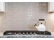 A gray tile backsplash is accented by a modern gas range and a decorative tea kettle at 14160 Ivanhoe St, Thornton, CO 80602