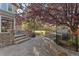 Beautiful stone backyard patio and pathway leading to a hot tub, surrounded by mature trees and flowering bushes at 14582 Homestead Pl, Broomfield, CO 80023
