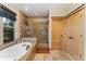 Bright bathroom featuring a glass-enclosed shower with tile surround, soaking tub, and light wood door at 14582 Homestead Pl, Broomfield, CO 80023