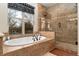 Bathroom featuring a soaking tub near the window, and a glass-enclosed shower with a tile surround at 14582 Homestead Pl, Broomfield, CO 80023