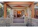 Covered outdoor patio with comfortable seating, stone pillars, and access to the home's interior at 14582 Homestead Pl, Broomfield, CO 80023