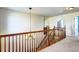 Well-lit hallway with wooden banister, carpeted stairs, and decorative chandelier at 3224 White Oak St, Highlands Ranch, CO 80129