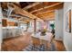 Dining area featuring exposed wood beams, brick wall, and seamless connection to the kitchen and living area at 1745 Wazee St # 3C, Denver, CO 80202